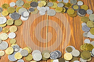 Frame from coins on wooden background and copy space for text in center. Finance concept.