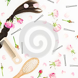 Frame with combs for hair styling, barrette and pink flowers on white background. Beauty blog composition. Flat lay, top view