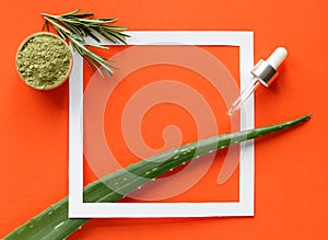 Frame with cometic ingredients on an orange background. Aloe vera and green powder