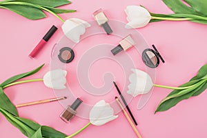 Frame composition with white tulips and cosmetics on pink background. Top view. Flat lay home feminine desk.