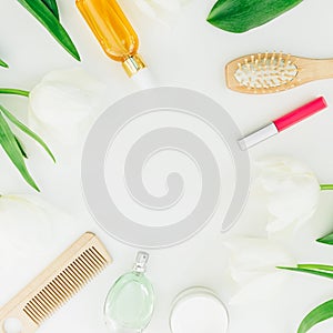 Frame with cosmetics, perfume, combs and tulips flowers on white background. Beauty blog composition. Flat lay, top view