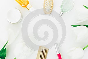 Frame with cosmetics, perfume, combs and tulips flowers on white background. Beauty blogger composition. Flat lay, top view