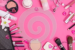 Frame of cosmetics on a pink background with a white flower. Flat lay