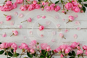 Frame with delicate pink roses on white old wooden background