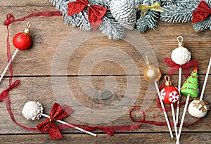 Frame of Christmas themed cake pops on wooden table, flat lay. Space for text