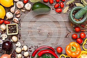 Frame of different fresh organic vegetables and spices on wooden table. Healthy natural food background with copy space.