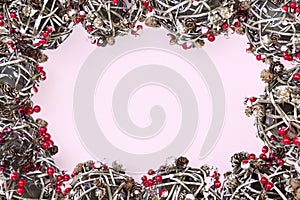 Frame of fir branches, red berries, balls, pine cones, Christmas decoration on pink background. Merry Christmas composition, New