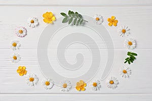 Frame of flowers and leaves on white wooden background, flat lay. Space for text