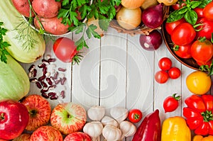 Frame of fresh vegetables and fruits on a white wooden table