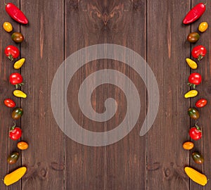 Frame from fresh vegetables like colorful cherry tomatoes and mini peppers on rustic wooden background with copy space