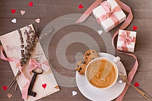 Frame of gifts, key, letter, cup of amazing coffee and hearts on wooden background. Valentine`s day.