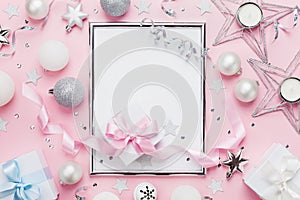 Frame with holiday balls, gift box and sequins on stylish pink table top view. Fashion christmas background. Flat lay.