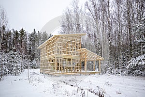frame house construction in winter, under the snow, in the forest. Fresh wood, frame of a two-story house