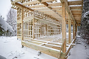 frame house construction in winter, under the snow, in the forest. Fresh wood, frame of a two-story house