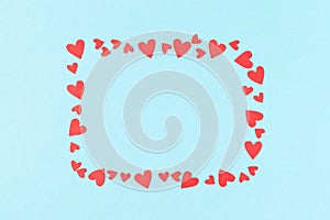 Frame for inscriptions from red cut out and paper hearts on a blue background greeting card for valentine`s day copy space