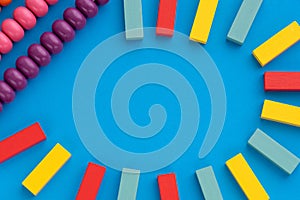 Frame from kids toys, top view on children`s educational games on blue paper background. Multicolored wooden bricks