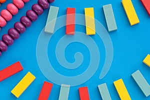 Frame from kids toys, top view on children`s educational games on blue paper background. Multicolored wooden bricks