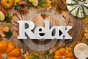 Frame of leaves and pumpkins on wooden background and the word `relax`