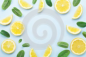 Frame from lemon slices and mint leaves on blue pastel table top view. Ingredients for summer drink and lemonade. Flat lay style.