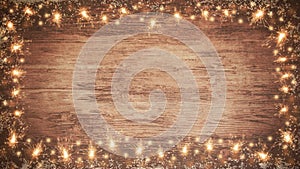 Frame of lights bokeh flares and sparkler isolated on rustic brown wooden texture - holiday New Year`s Eve background banner
