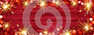 Frame of lights bokeh golden flares and sparkler isolated on rustic red wooden texture - Holiday New Year`s Eve Silvester New Yea