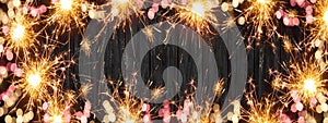 Frame made bokeh lights, sparklers and fireworks isolated on rustic wooden table texture - holiday New Year`s Eve background