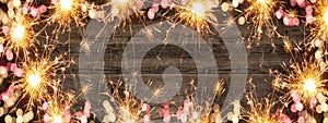 Frame made bokeh lights, sparklers and fireworks isolated on rustic wooden table texture - holiday New Year`s Eve background