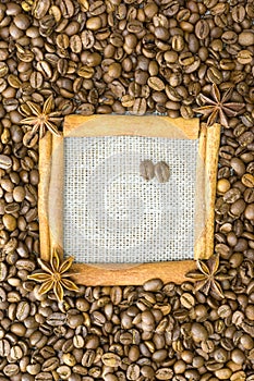 The frame is made of cinnamon , star anise , around the grain roasted coffee on a background of linen . A place for your inscripti