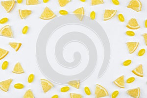 Frame made with fresh lemon slices and tasty candies on table, flat lay. Space for text