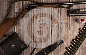 The frame is made of hunting weapons, a bandoleer with cartridges, binoculars in a case, a knife in a sheath, equipment for cleani