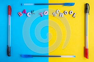Frame made of multi-colored ballpoint pens on a yellow and blue background. Inscription from colored letters back to school.