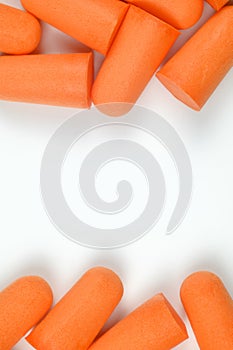 Frame made of orange earplugs on a white background. Close-up. Soft foam earplug