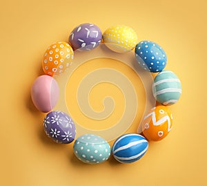 Frame made of painted Easter eggs on color background, top view
