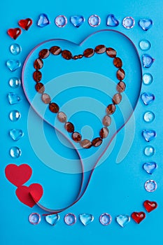 In a frame made of pebbles of hearts on a blue background, a ribbon in the shape of a heart.