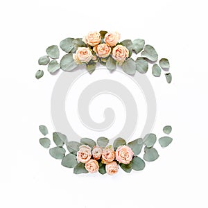 Frame made of pink roses, green leaves eucalyptus, branches, floral pattern on white background. Flat lay, top view