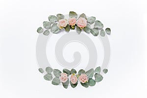 frame made of pink roses, green leaves eucalyptus, branches, floral pattern on white background. Flat lay, top view