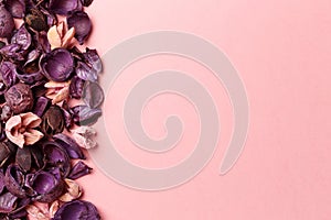 Frame made of purple and pink dry flowers, branches, leaves and petals on pastel pink background. Colorful background image