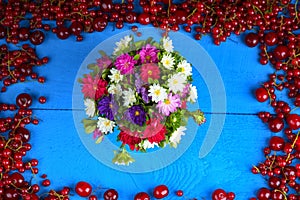 Frame made of red currant and cherry with flower bouquet