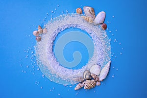 Frame made of sea salt for exfoliation on blue background with sea shells