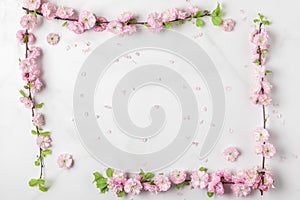 Frame made of spring pink cherry blossom branches on white marble background. Flat lay. Holiday or wedding layout