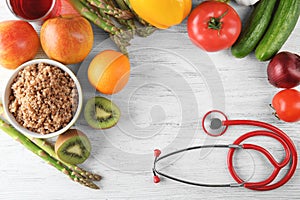 Frame made with stethoscope, fresh fruits and vegetables on wooden background. Healthy food concept