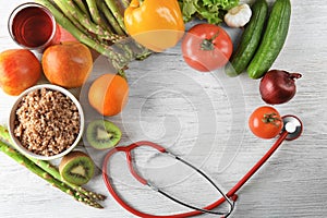 Frame made with stethoscope, fresh fruits and vegetables on wooden background. Healthy food concept