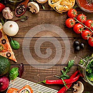 Frame made of vegetables, pizza, sushi rolls, tomato, pasta, olives and sauce on wooden background. Food concept for menu. Flat la