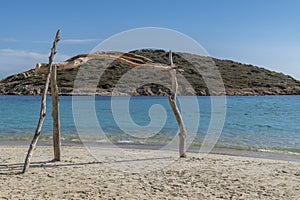 A frame made of wooden logs on the beach of Tuerredda, Sardinia, Italy and the Tuaredda island in the background photo