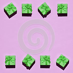 Frame of many small green gift boxes on texture background of fashion trendy pastel pink color paper