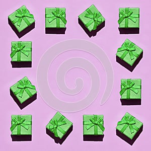 Frame of many small green gift boxes on texture background of fashion trendy pastel pink color paper