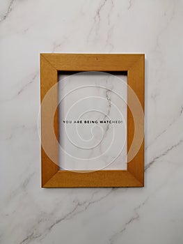 A frame on marble wall with wording you are being watched.