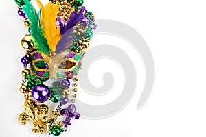 Frame of Mardi Gras mask and beads isolated on white background.