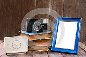 Frame with old books and old camera on wood table