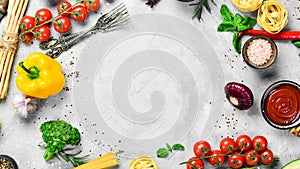 Frame of organic food. Fresh raw vegetables with spices, basil and rosemary on a gray stone background.